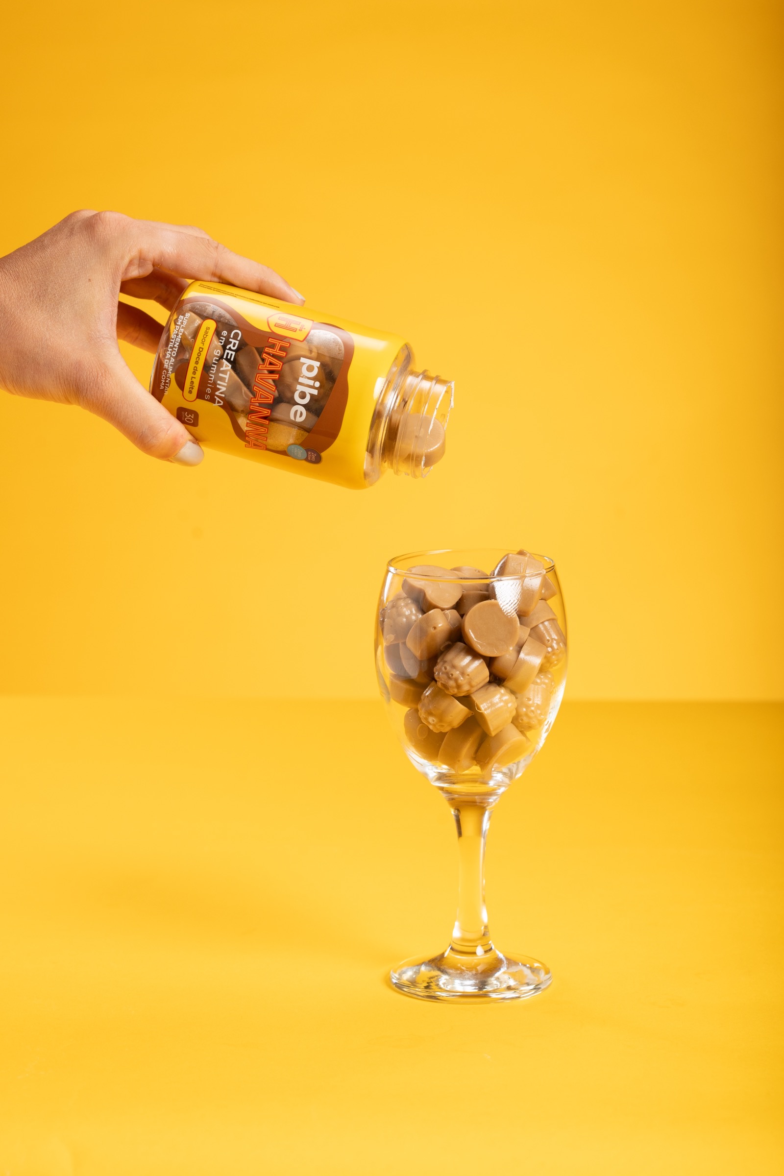 Gummies de Pibe Havanna Creatina sendo despejados do pote em uma taça de vidro